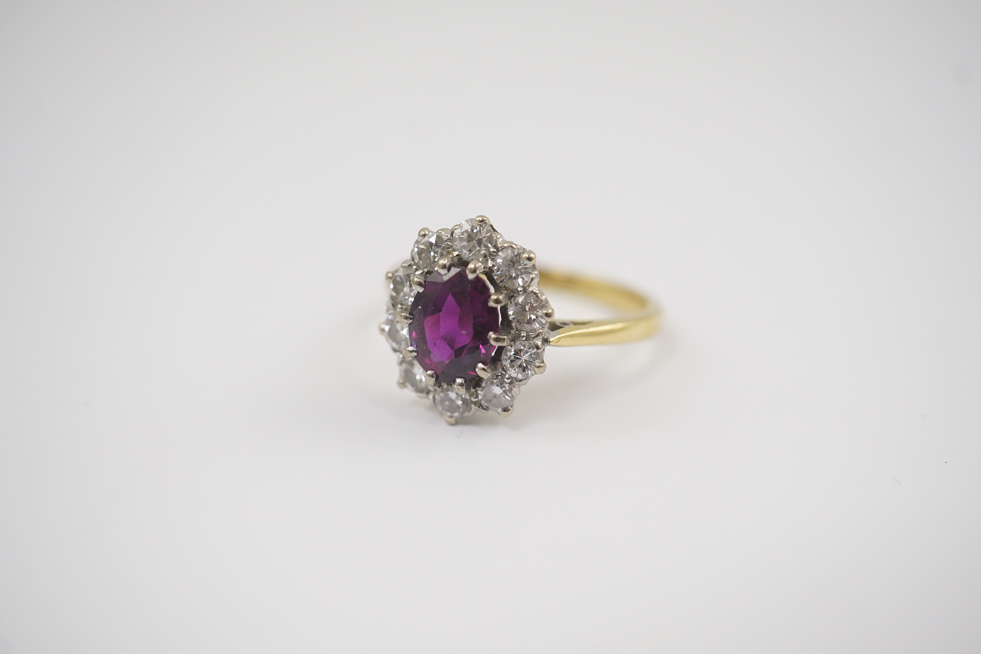 An 18ct gold and platinum, ruby and diamond set oval cluster ring